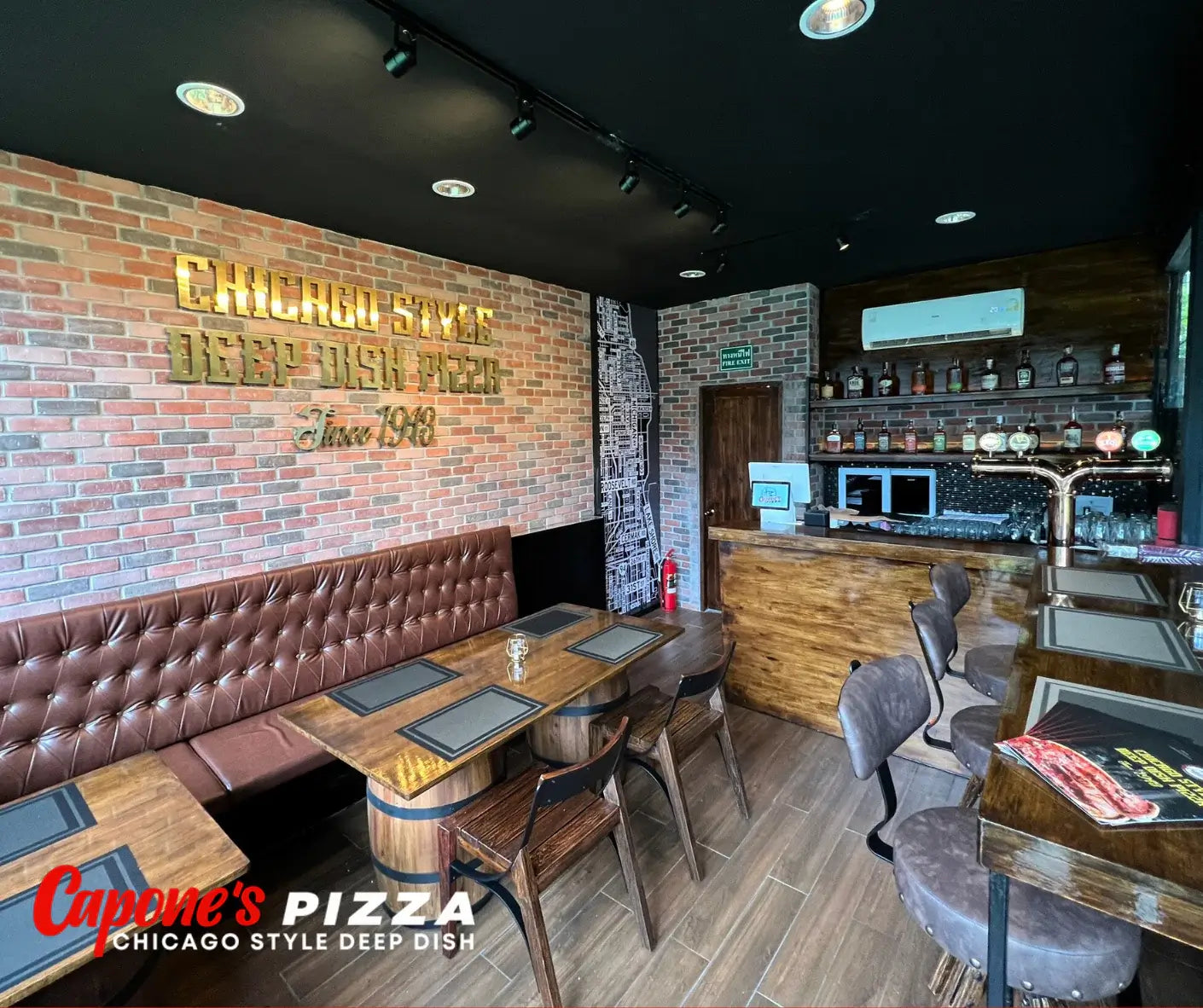 Restaurant interior with brick wall and 'Capone's Pizza' branding