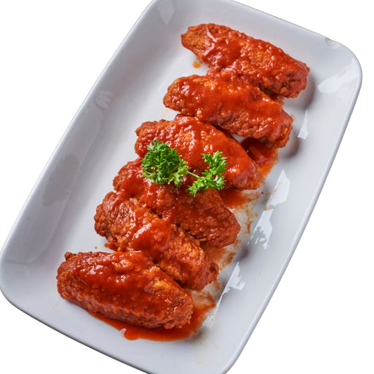 A plate of buffalo wings with sauce and a sprig of parsley on top.