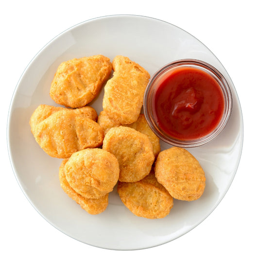 A plate of chicken nuggets next to a ketchup bottle.